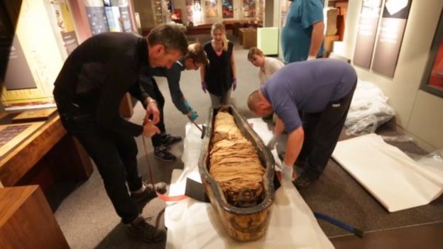 Nesyamun's mummified remains being lifted out of a coffin at Leeds City Museum