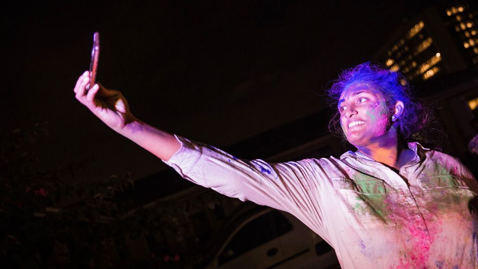 A woman covered in coloured powder takes a selfie during the Hindu Holi festival in Durban, South Africa - Monday 9 March 2020